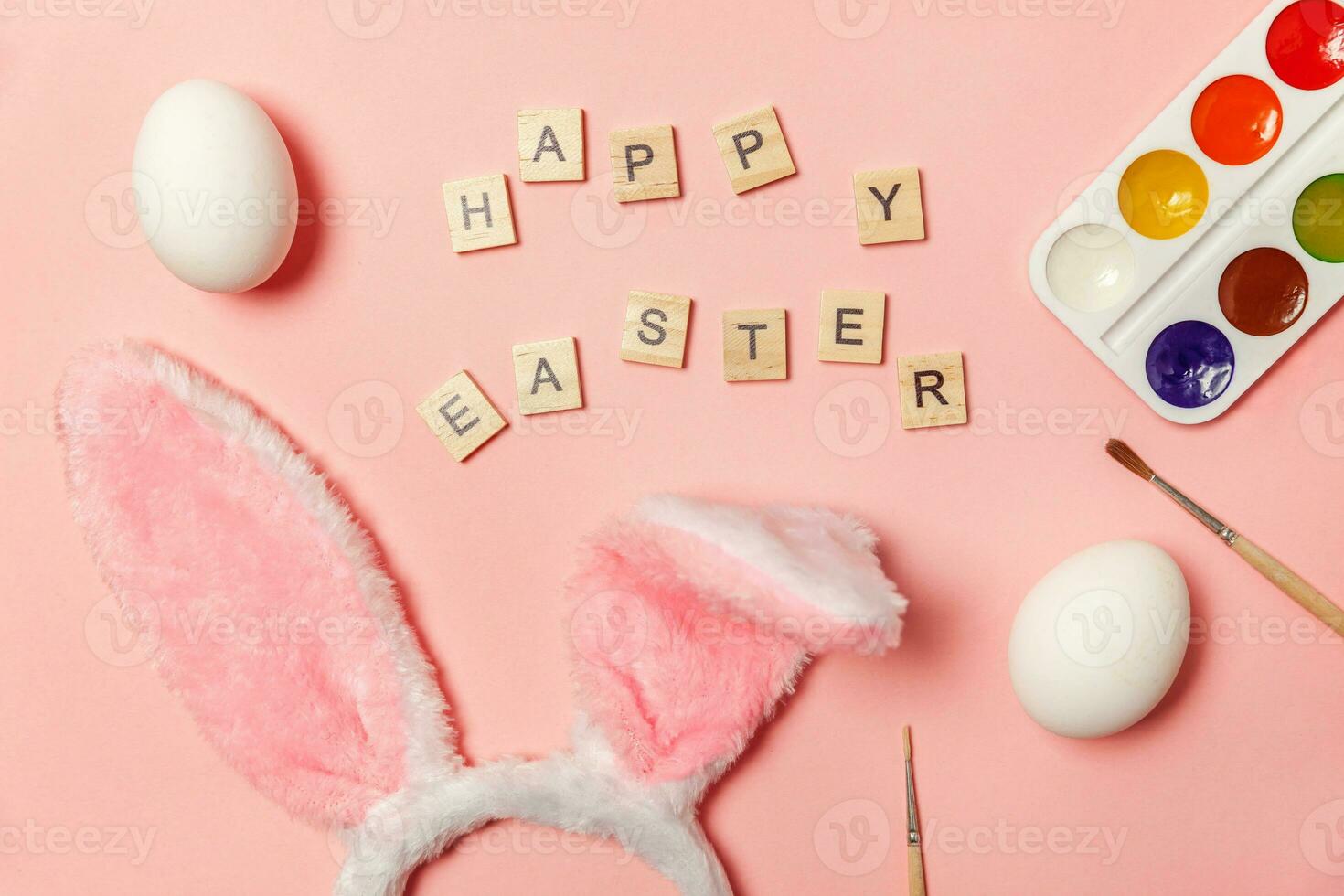 Inscription HAPPY EASTER letters eggs colorful paints and bunny ears isolated on trendy pink background photo