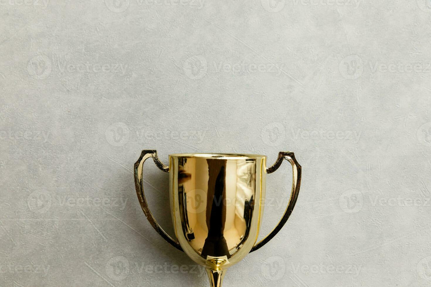 Simply flat lay design winner or champion gold trophy cup on concrete stone grey background. Victory first place of competition. Winning or success concept. Top view copy space. photo