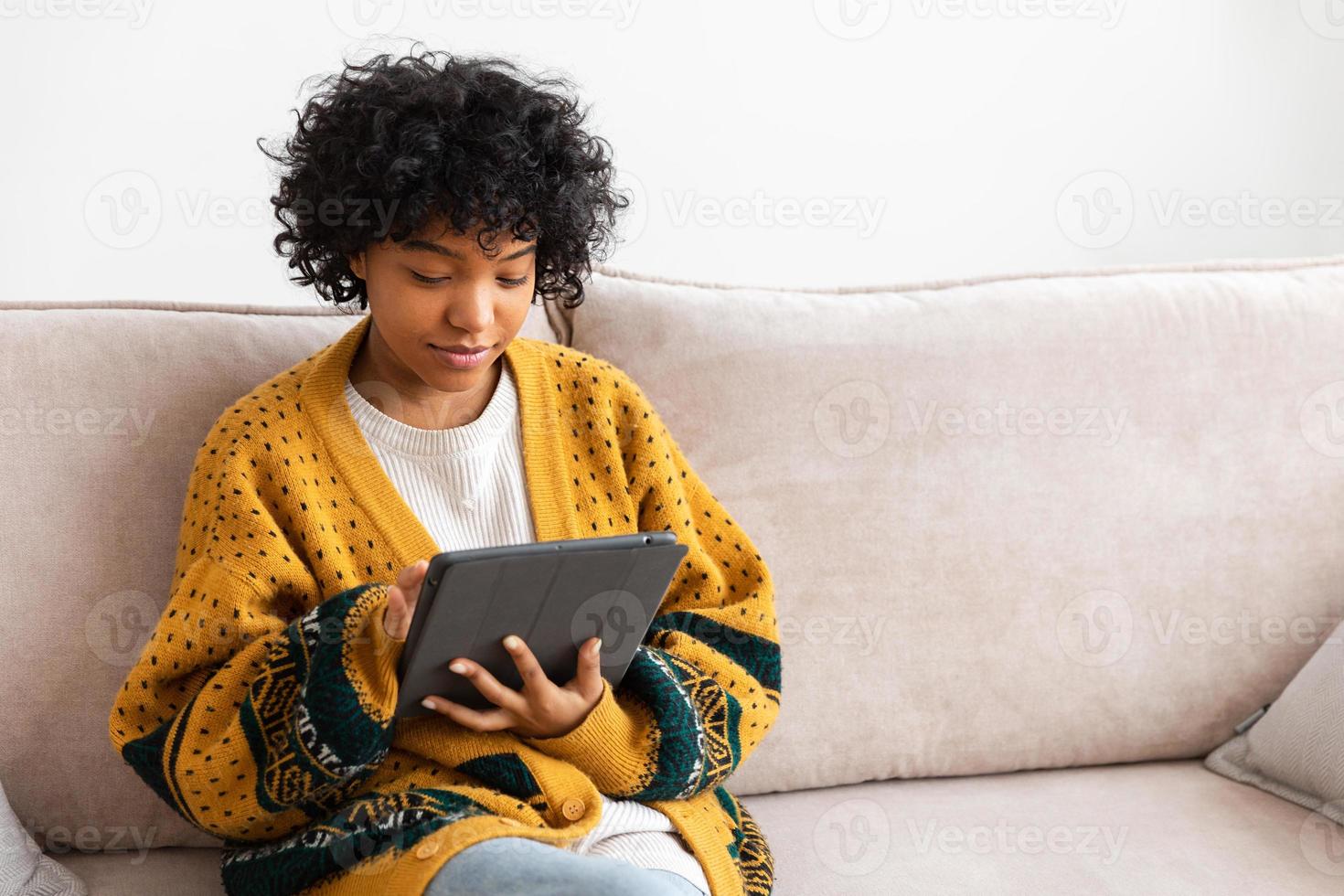 African american girl holding digital tablet touch screen typing scroll page at home. Woman with mobile tech device surfing internet using social media apps playing game. Study work shopping online. photo