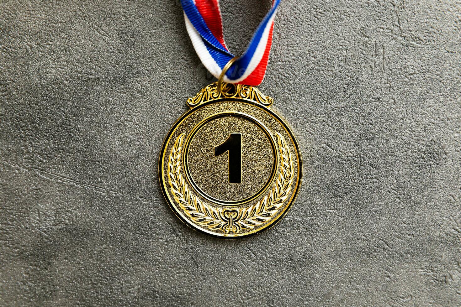 Simply flat lay design winner or champion gold trophy medal on concrete stone grey background. Victory first place of competition. Winning or success concept. Top view flat lay copy space. photo