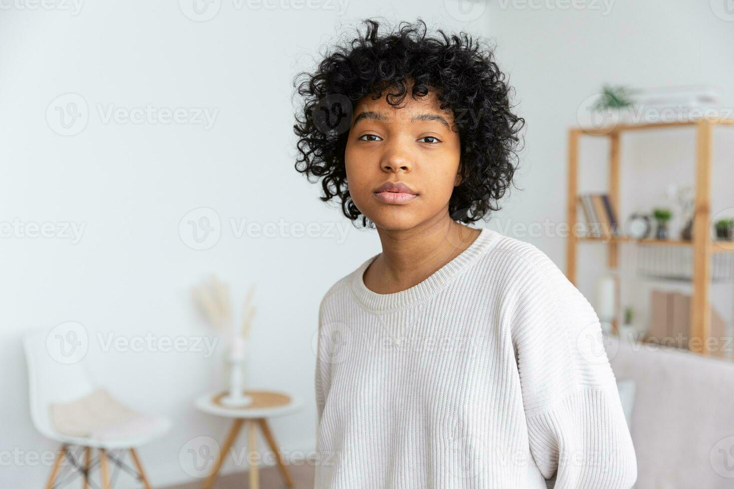 Beautiful african american girl with afro hairstyle at home indoor. Young african woman with curly hair in living room. Beauty ethnic people, domestic life concept. photo