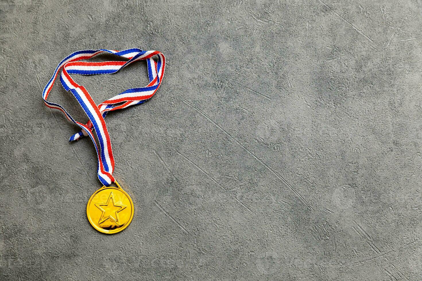 Simply flat lay design winner or champion gold trophy medal on concrete stone grey background. Victory first place of competition. Winning or success concept. Top view flat lay copy space. photo