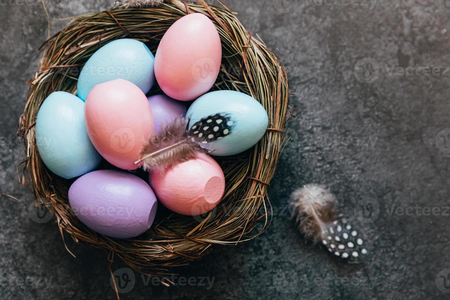 Happy Easter concept. Preparation for holiday. Colorful pastel decorated easter eggs in nest on grunge scratched dark black shale background. Simple minimalism flat lay top view copy space. photo