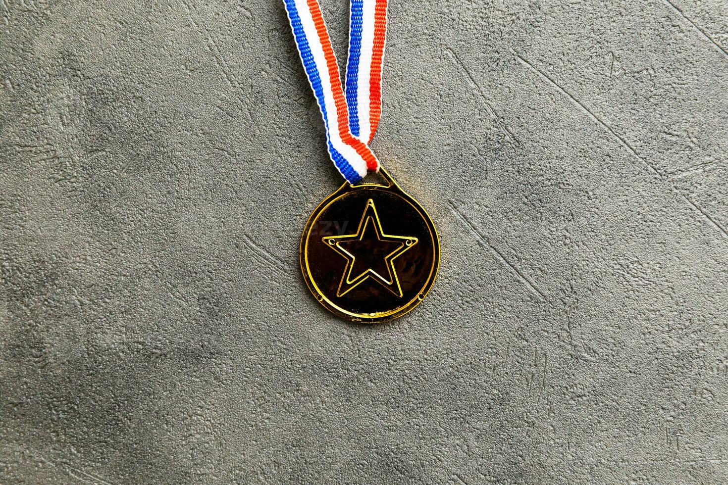 Simply flat lay design winner or champion gold trophy medal on concrete stone grey background. Victory first place of competition. Winning or success concept. Top view flat lay copy space. photo