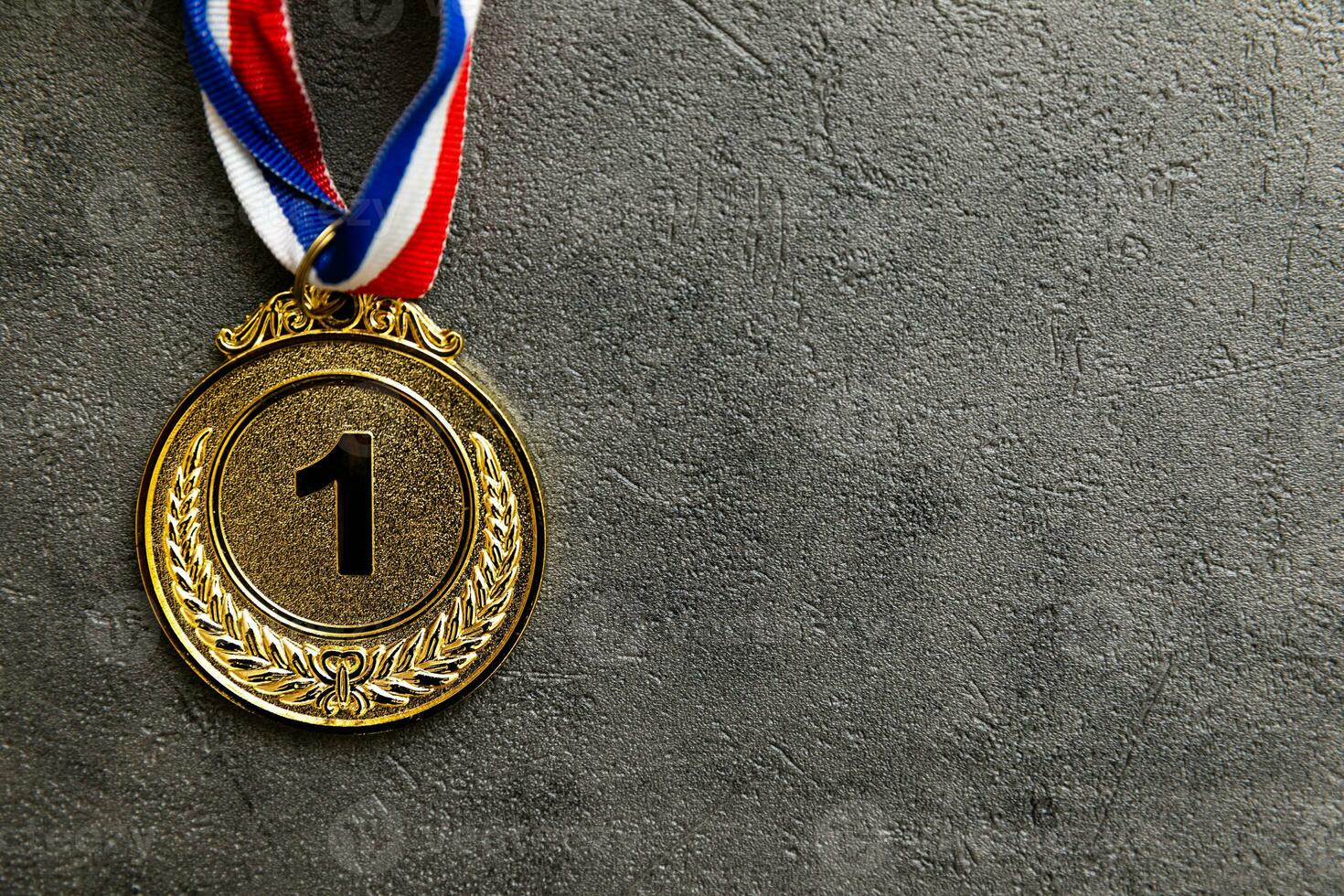Simply flat lay design winner or champion gold trophy medal on concrete stone grey background. Victory first place of competition. Winning or success concept. Top view flat lay copy space. photo
