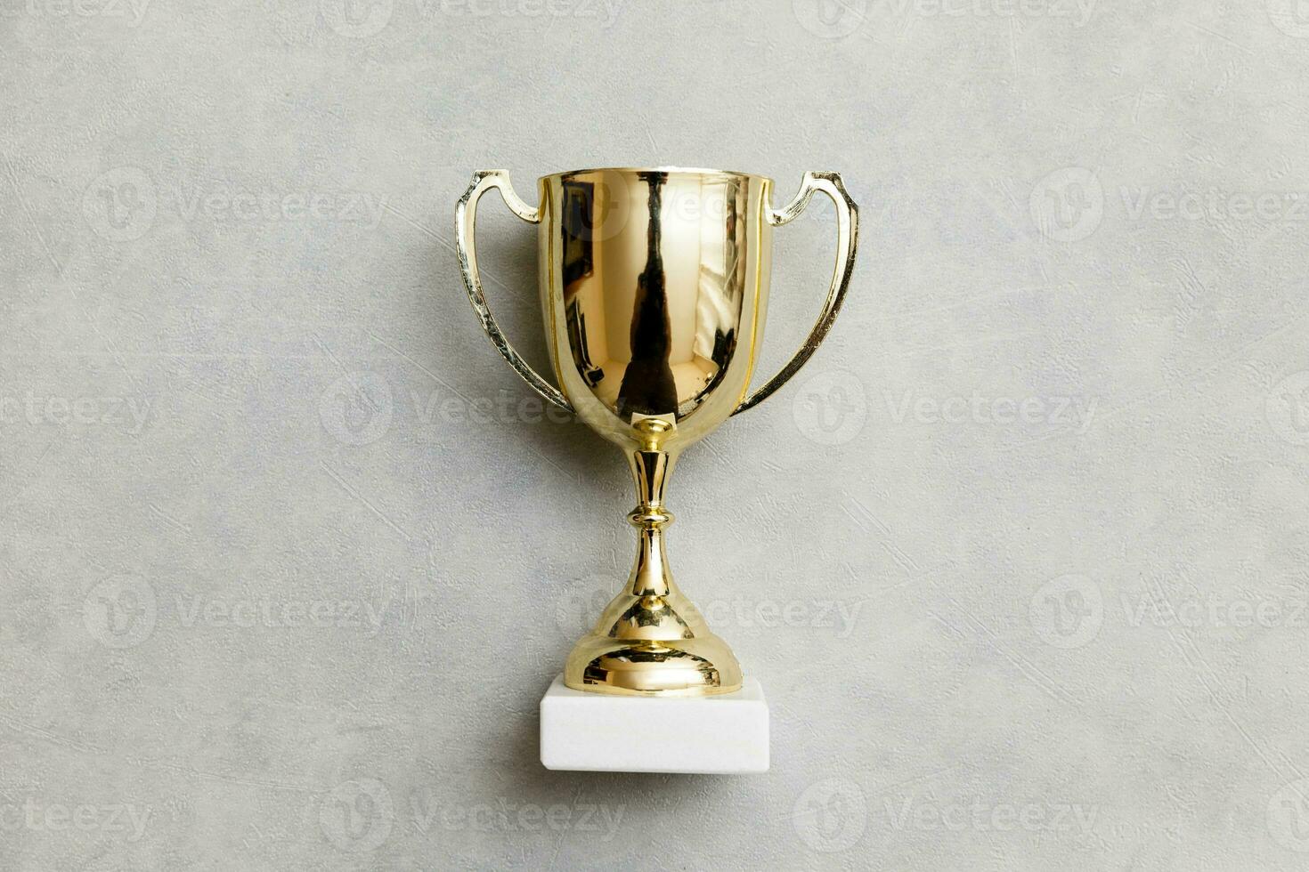 Simply flat lay design winner or champion gold trophy cup on concrete stone grey background. Victory first place of competition. Winning or success concept. Top view copy space. photo