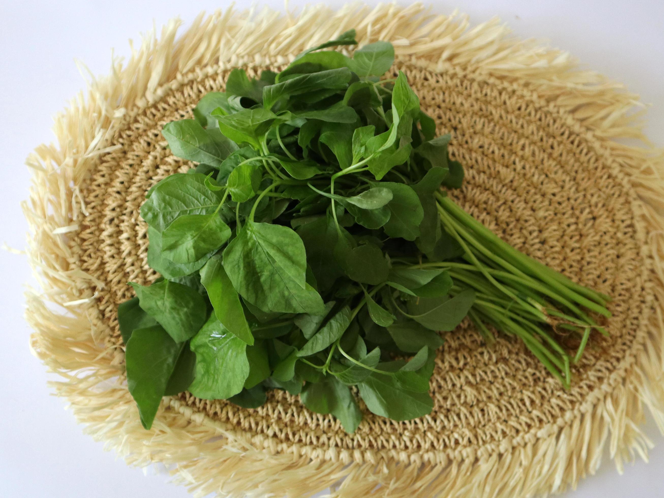 Green asparagus bunch on wicker tray on white table background