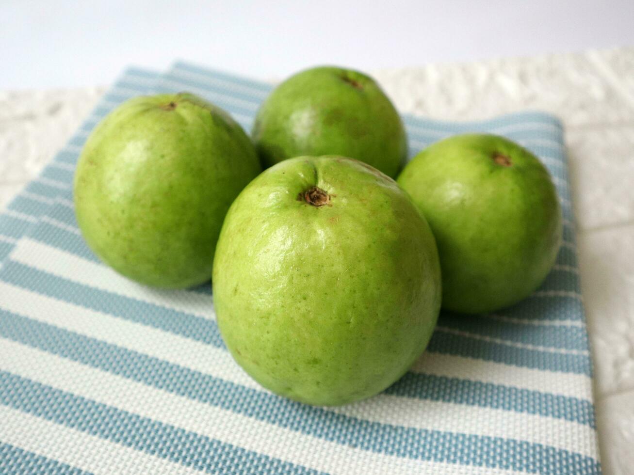 three fresh guavas on a striped blue cloth photo