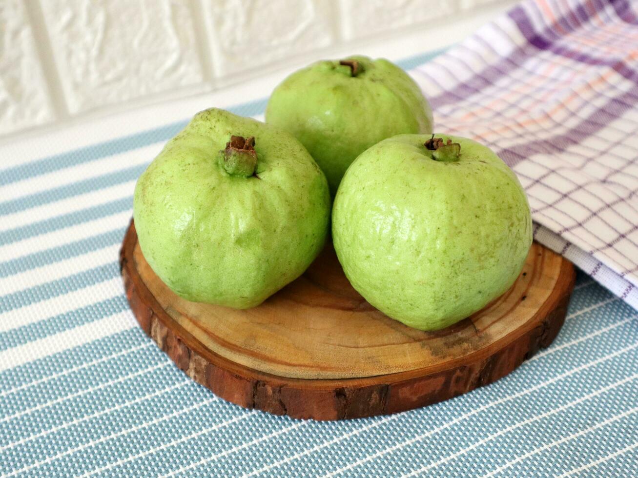 three fresh guavas on a striped blue cloth photo