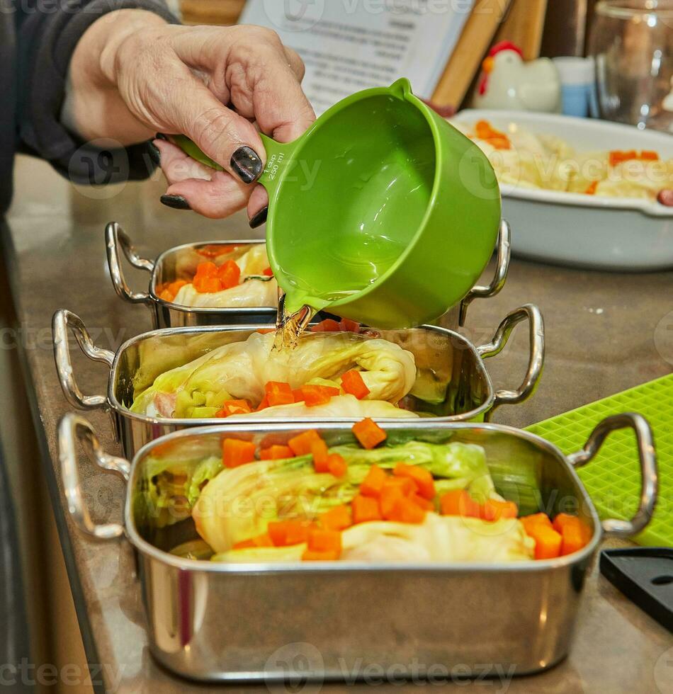 Chef pours sauce on cabbage rolls with salmon, carrots in the kitchen. French recipe photo