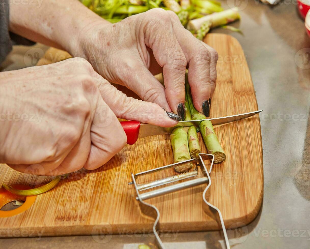 cocinero prepara espárragos en el cocina en de madera tablero según a receta desde el Internet foto