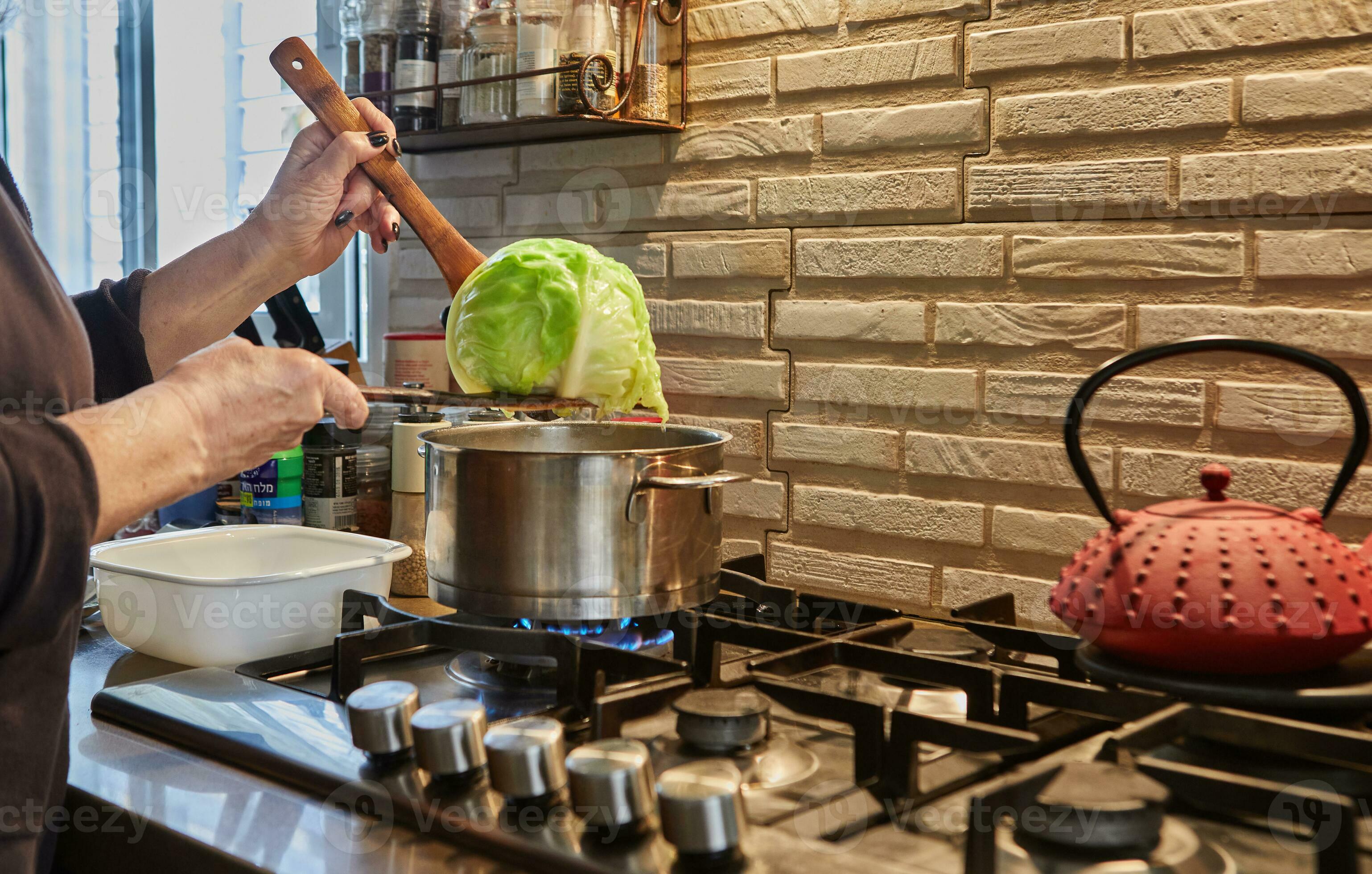 Chef takes boiled Cabbage out of the pot on the gas stove 20657783 Stock Photo at Vecteezy