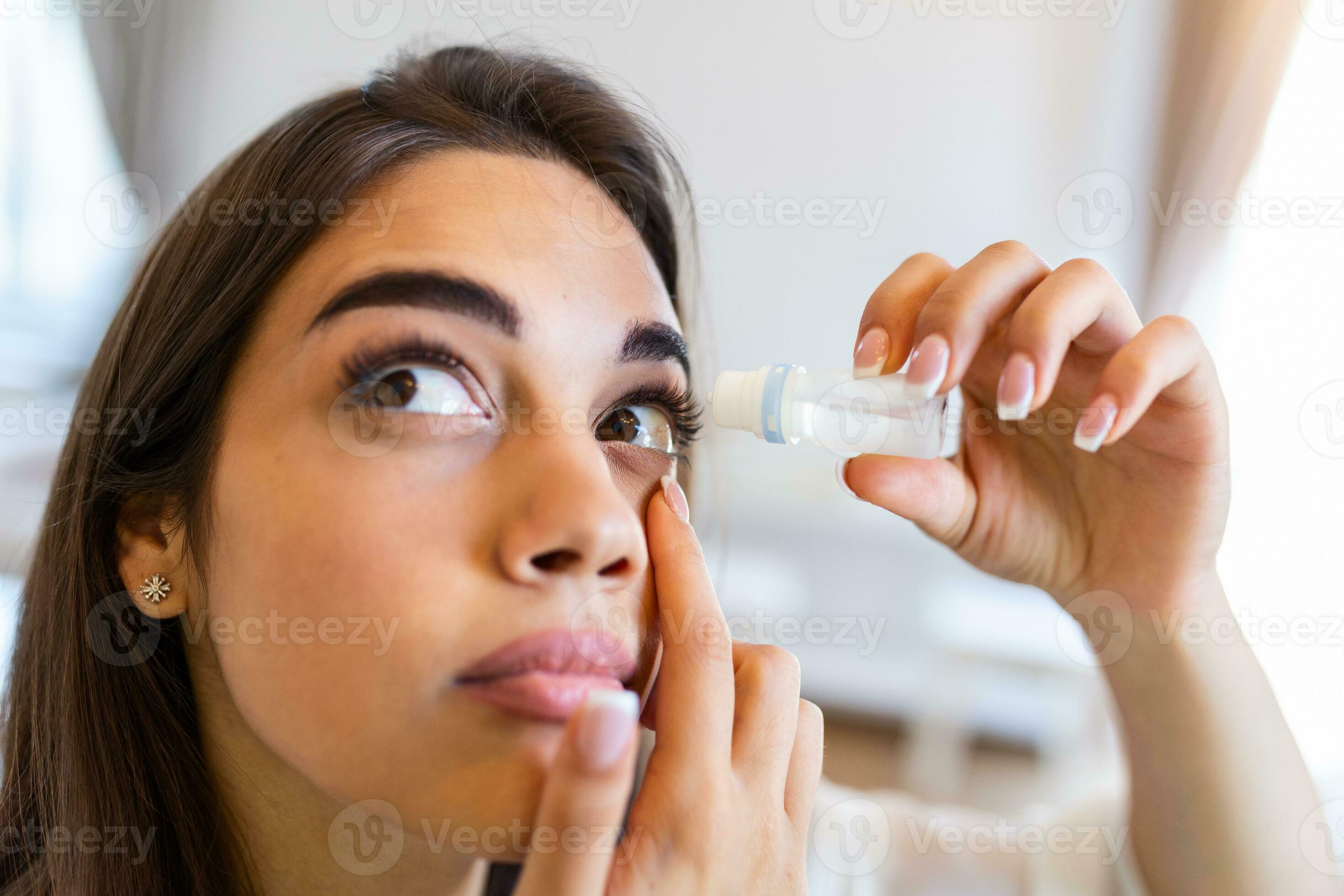 Photo of a woman using eye drop. Female dropping eye lubricant to treat