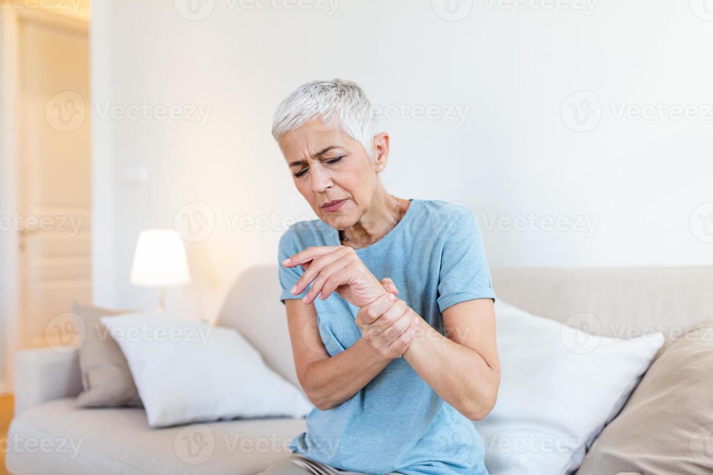 Elderly woman suffering from pain in hand, arthritis old person and senior woman female suffering from pain at home photo