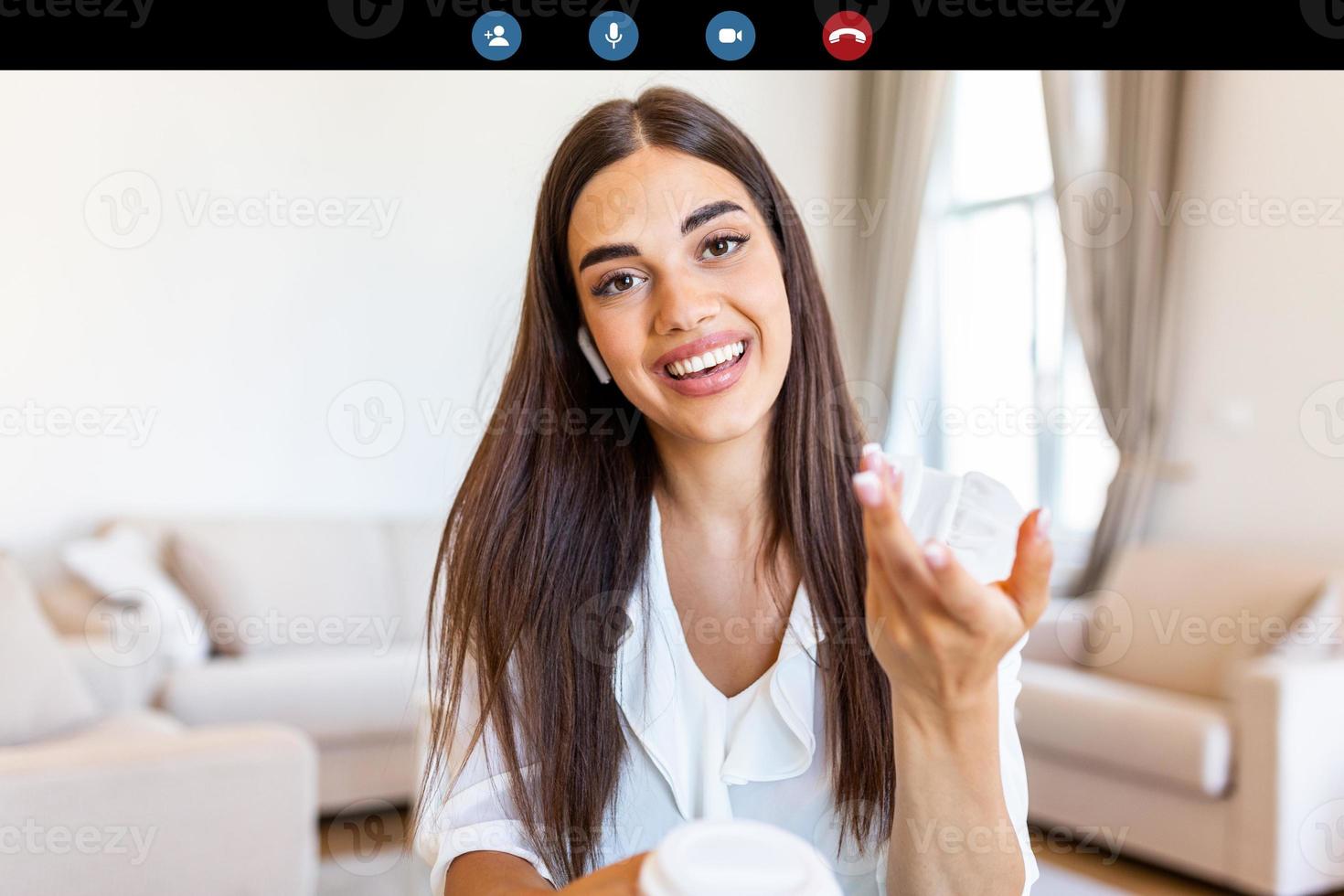 Attractive young woman smiling and looking at camera while having video call. Online teaching. Young woman wearing headphone photo
