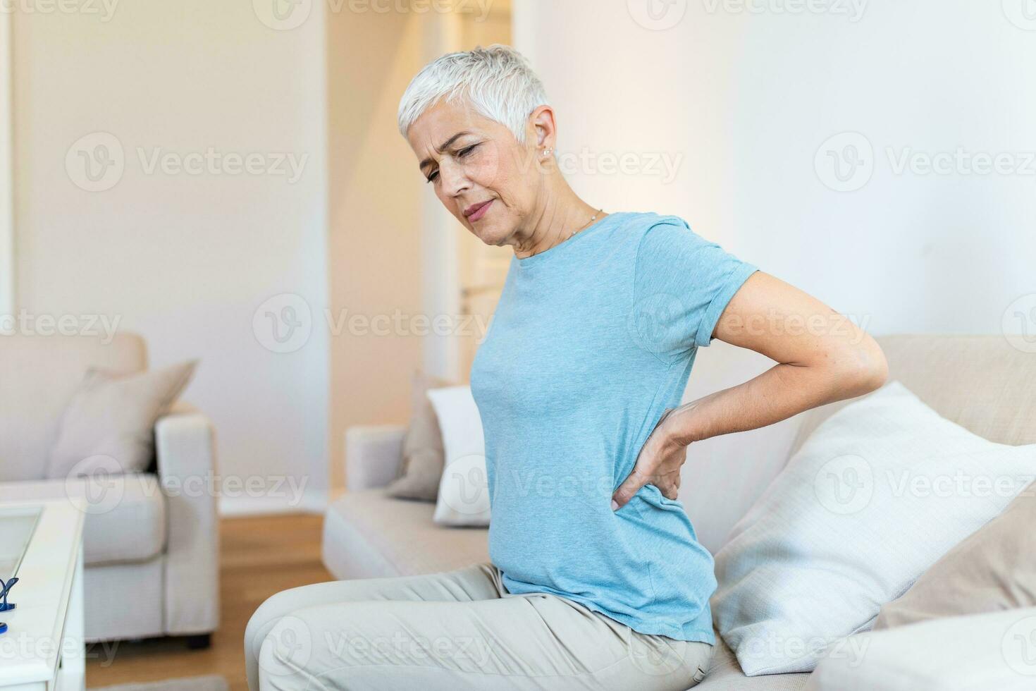 Upset mature middle aged woman feels back pain massaging aching muscles, sad senior older lady suffers from low-back lumbar pain sitting in incorrect sedentary posture, backache radiculitis concept photo