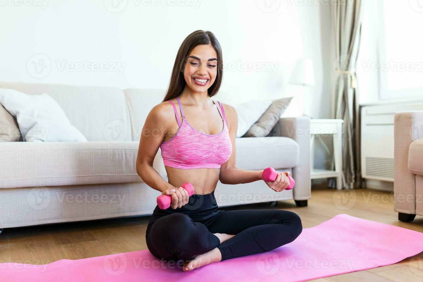 Young woman exercise with dumbbells at home and watching tutorial lesson on laptop computer. happy young female doing arm workout using dumbbells and looking at tutorial on her laptop photo