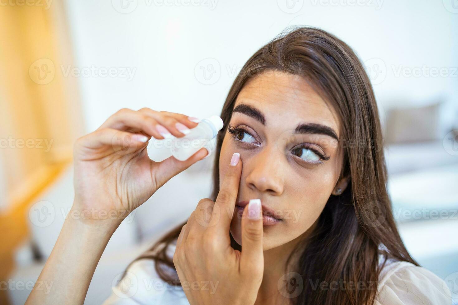 Vision And Ophthalmology Medicine. Closeup Of Beautiful Woman Applying Eyedrops In Her Eyes. Young Female Model With Natural Makeup Using A Bottle Of Eye Drops. Health Concept. High Resolution photo