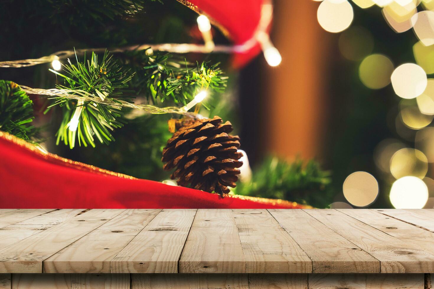 Empty wood table and christmas pine cones hanging from Christmas tree with display montage for product. photo