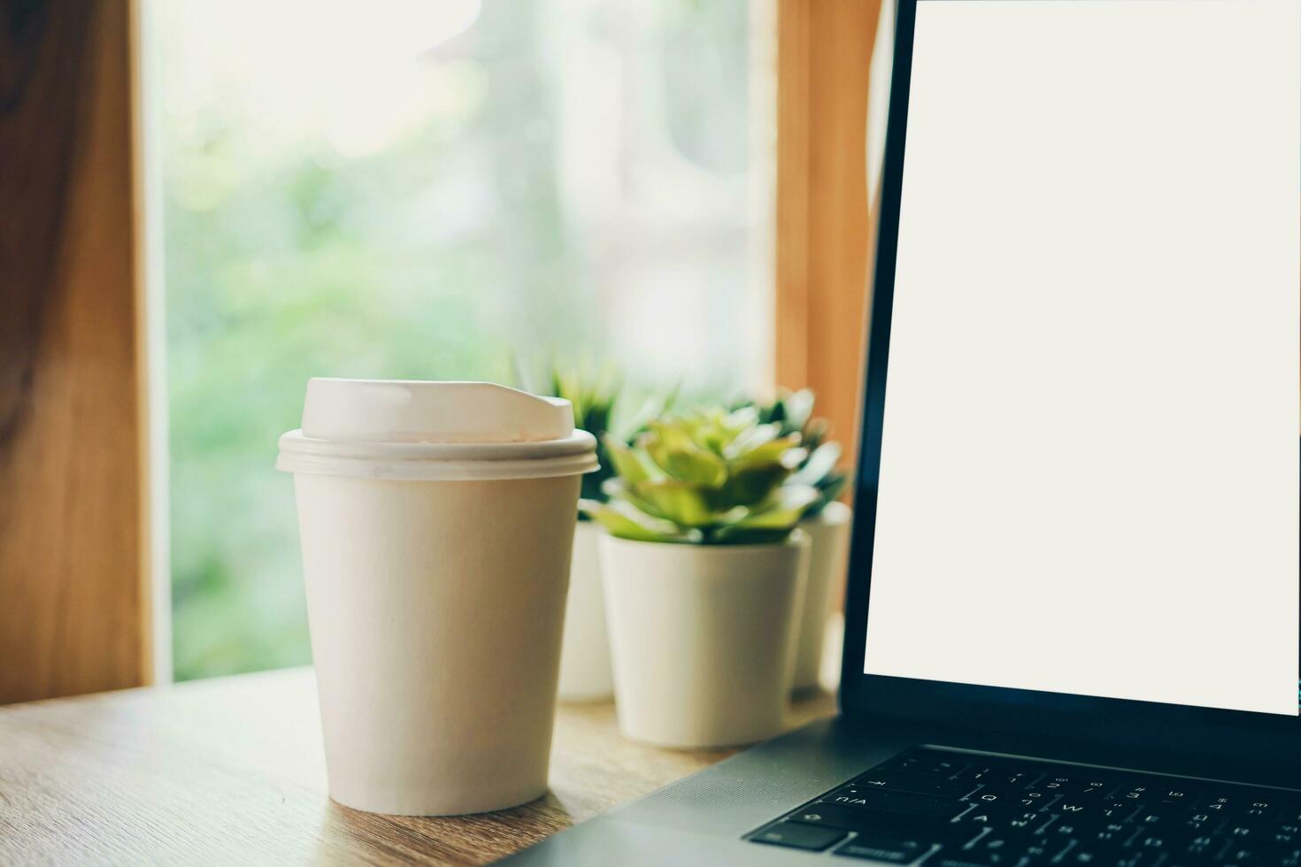 Cropped Image Of coffee and laptop on wooden table photo