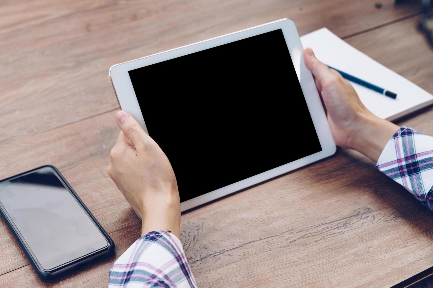 Hand woman using tablet computer on wooden table with Vintage toned. photo