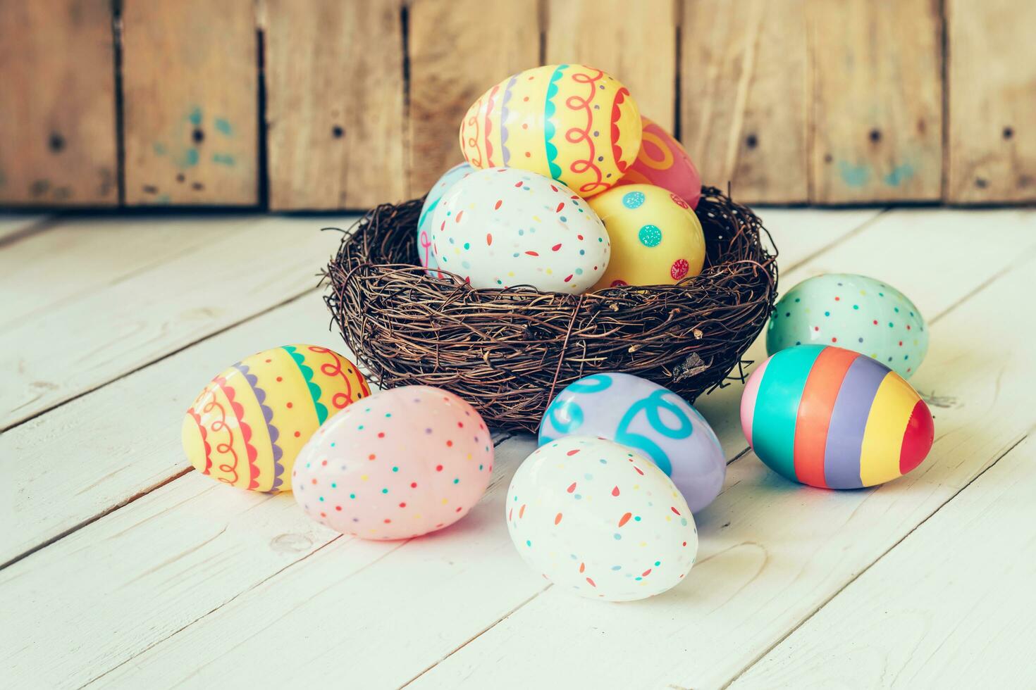 Colorful easter eggs in the nest on wood table background. photo