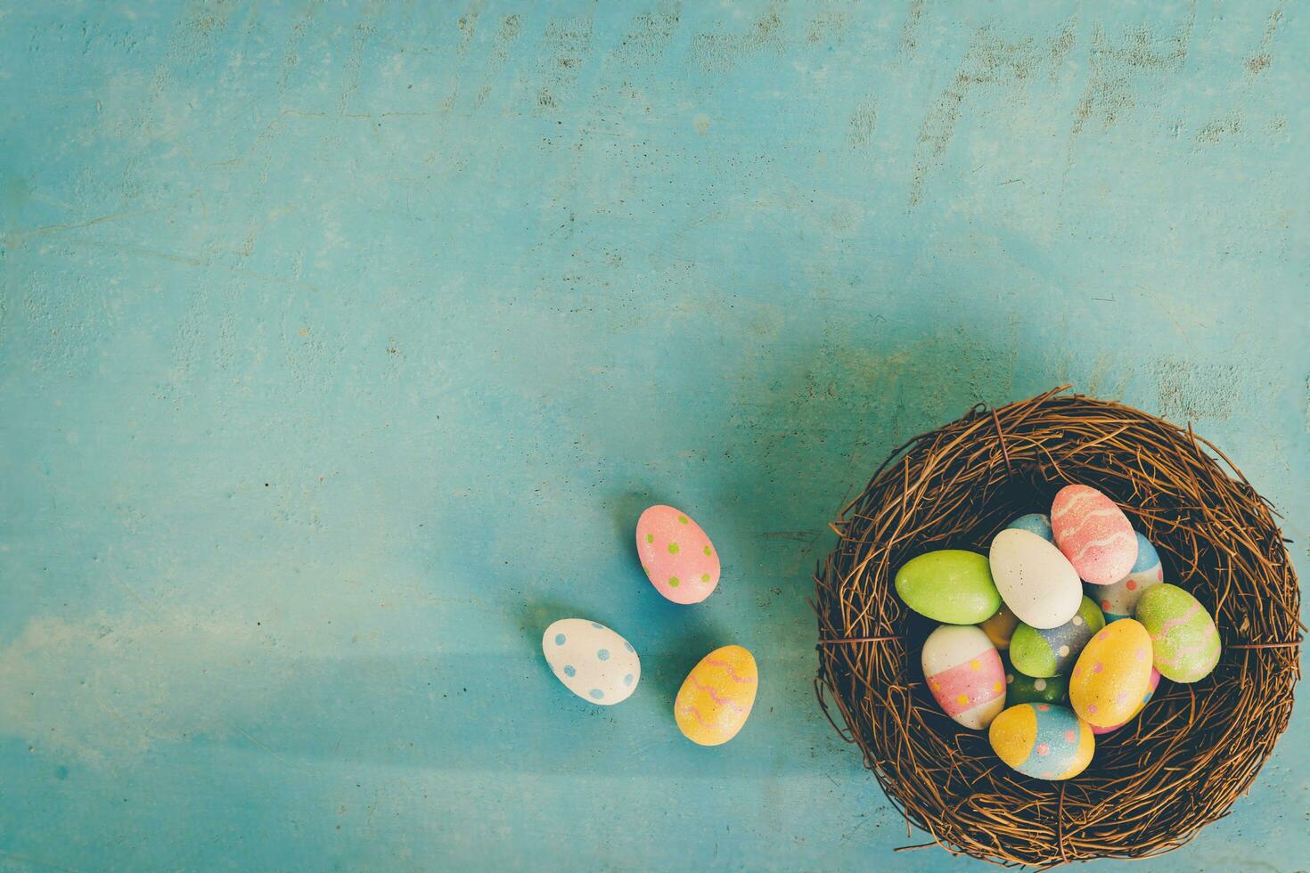 Colorful easter eggs in nest on blue wood background with copy space. photo