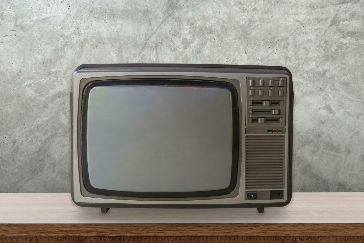 Vintage TV box on wooden table and cement wall background. photo