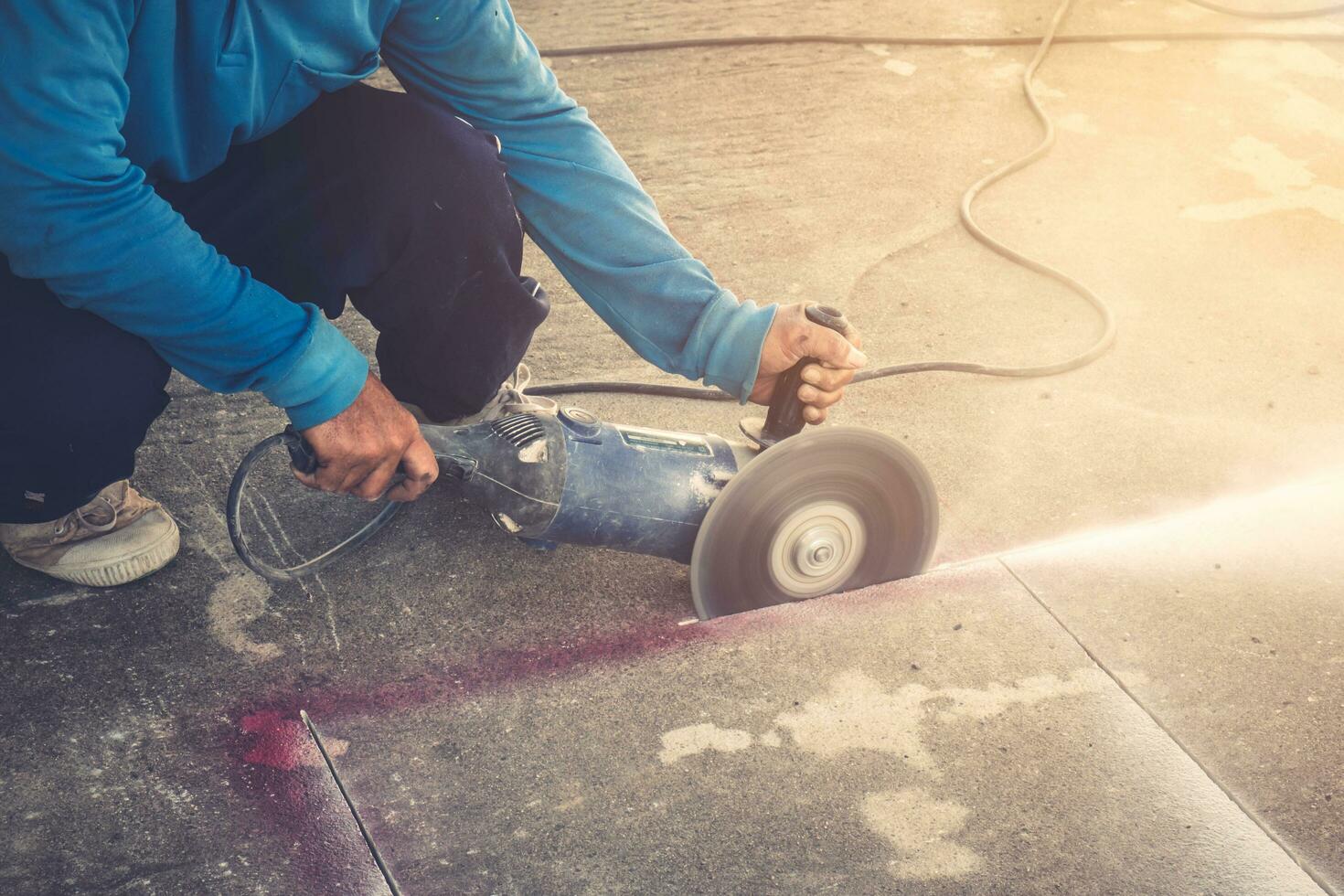 cerca arriba mano hombre corte hormigón piso con máquina. foto