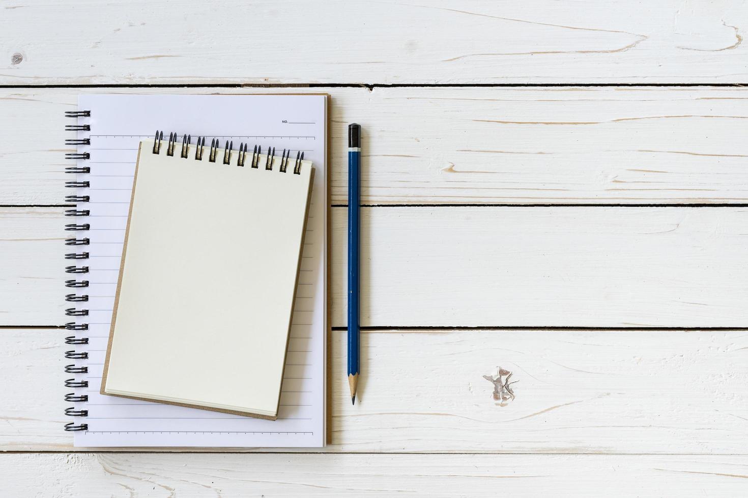 Open notebook with blank pages and pencil on wood table photo