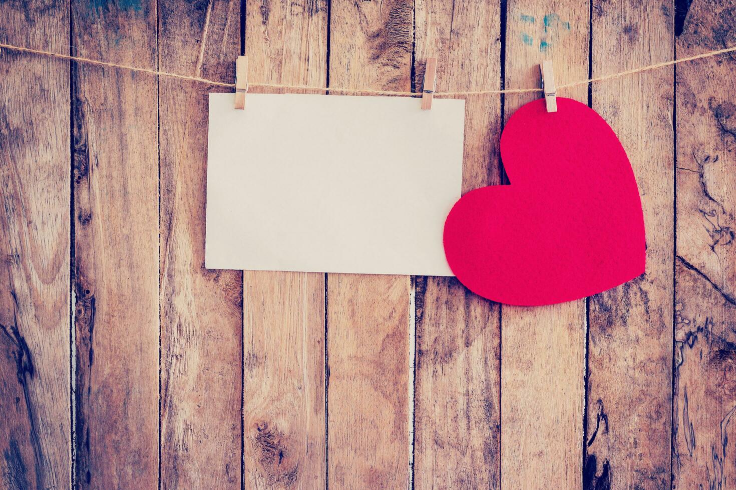 Red heart hanging and paper on clothesline and rope with wooden background photo