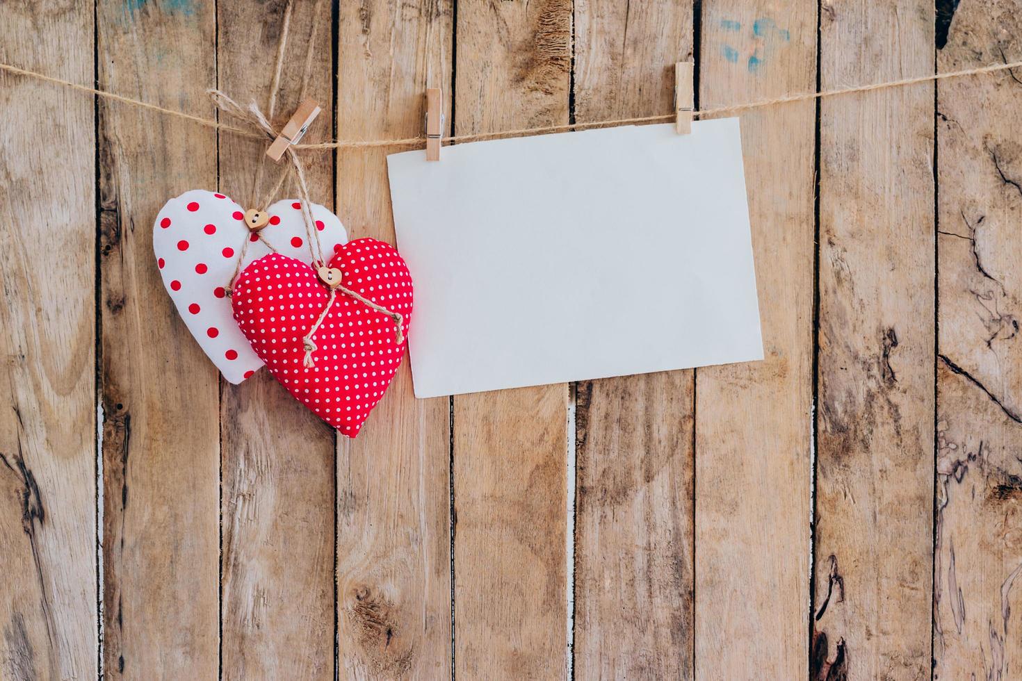 Two heart fabric and paper hanging on clothesline at wood background with space. photo