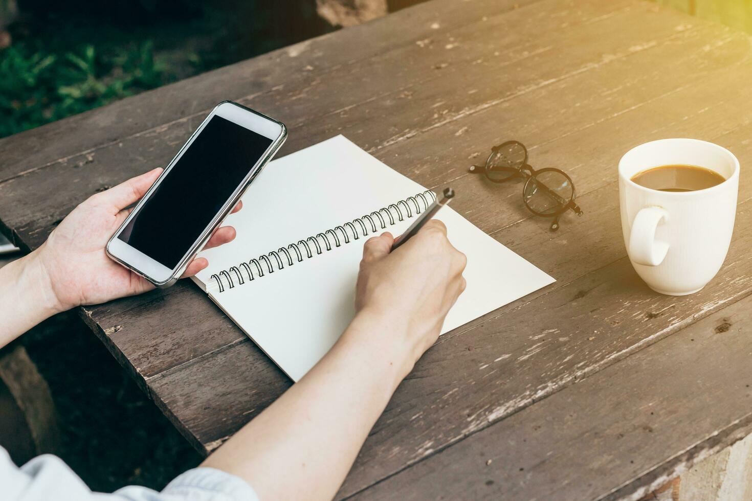 mano mujer escritura cuaderno y participación teléfono en madera mesa fondo con Clásico tonificado foto