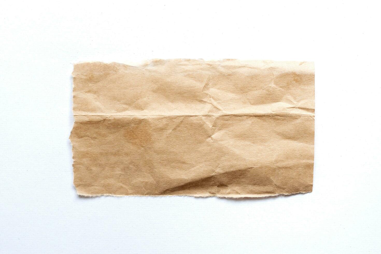Close up of a ripped piece of brown paper on white background photo
