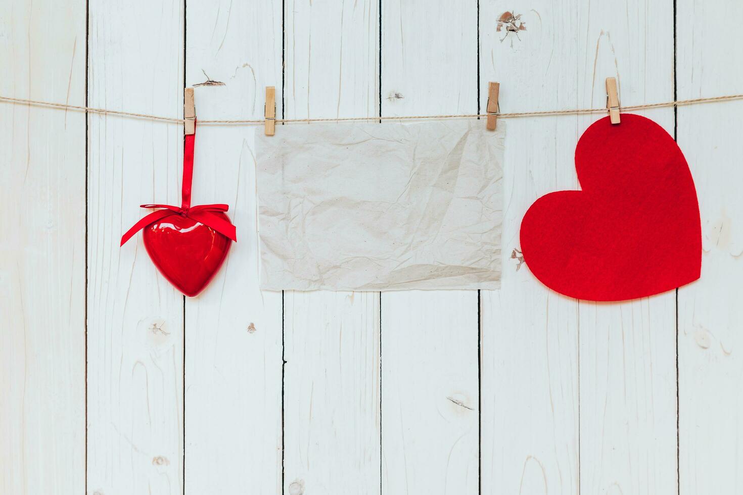 rojo corazón y antiguo papel blanco colgando a tendedero en madera blanco antecedentes con espacio. enamorado día. foto