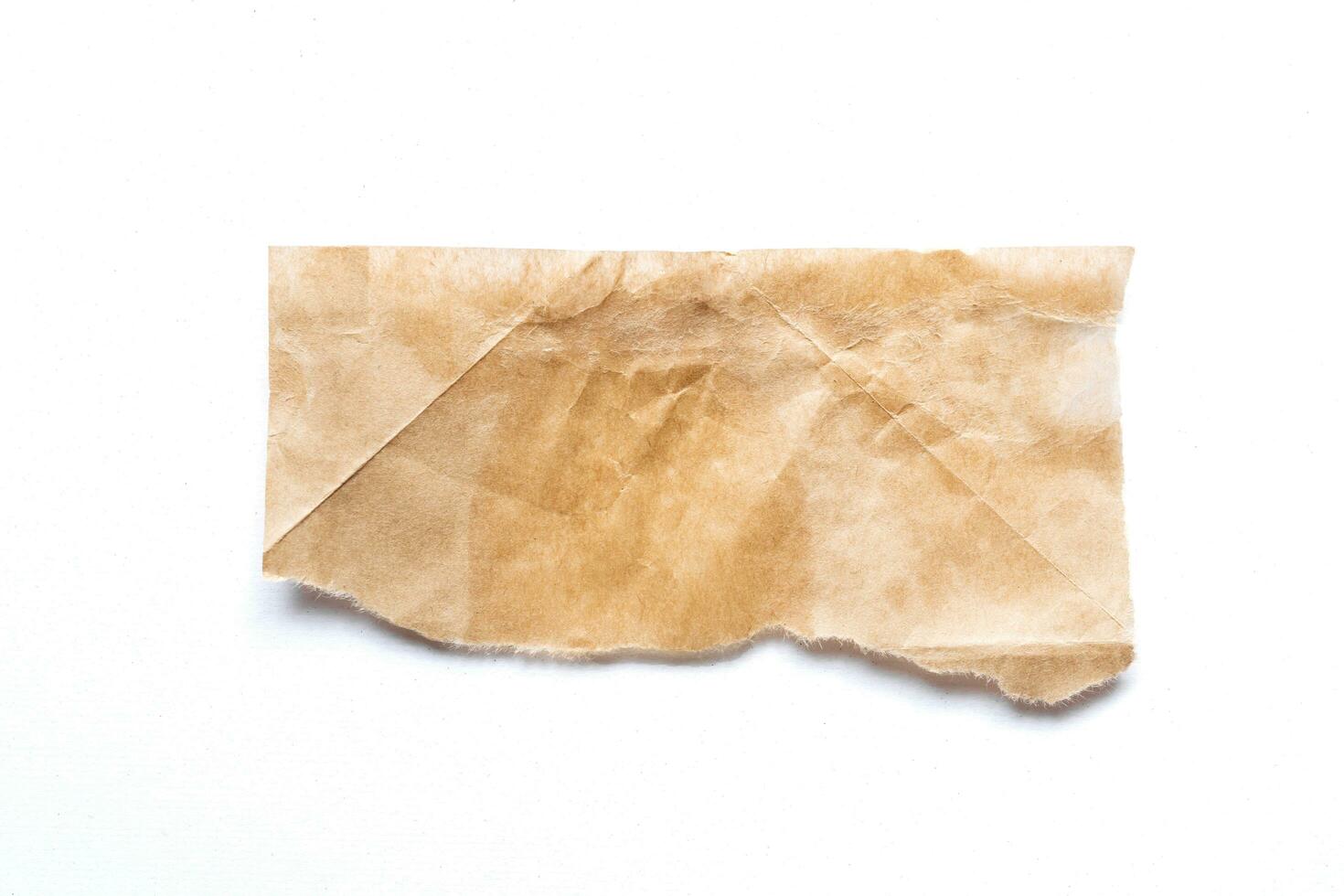 Close up of a ripped piece of brown paper on white background photo