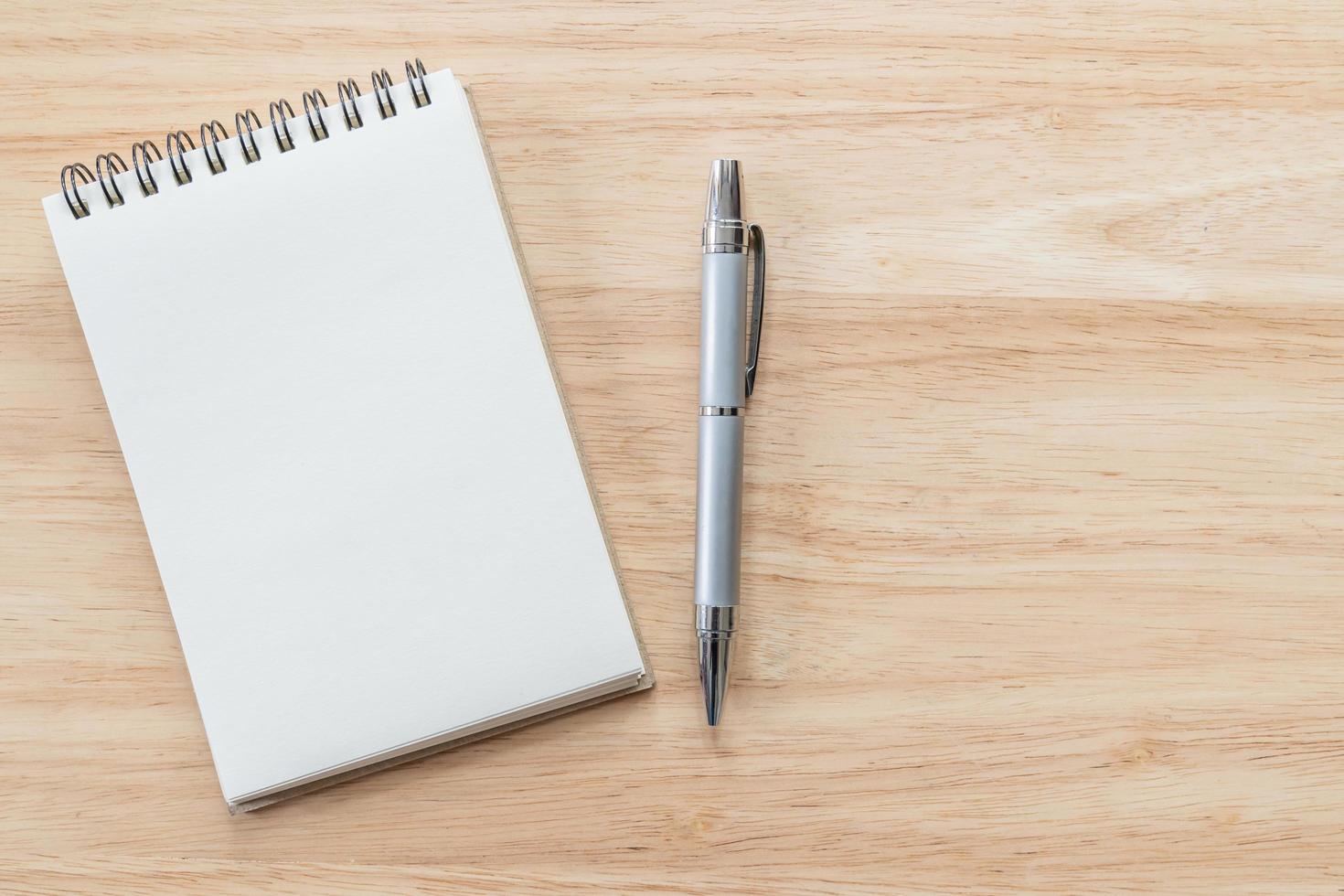 Top view of blank notebook with pen and natural light on wooden table. photo