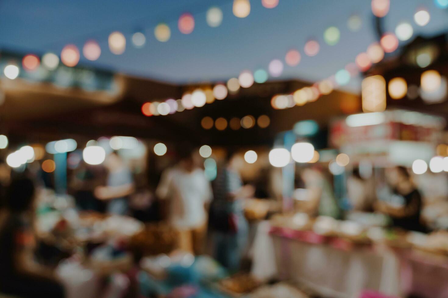 blurred background at night market festival people walking on road. photo