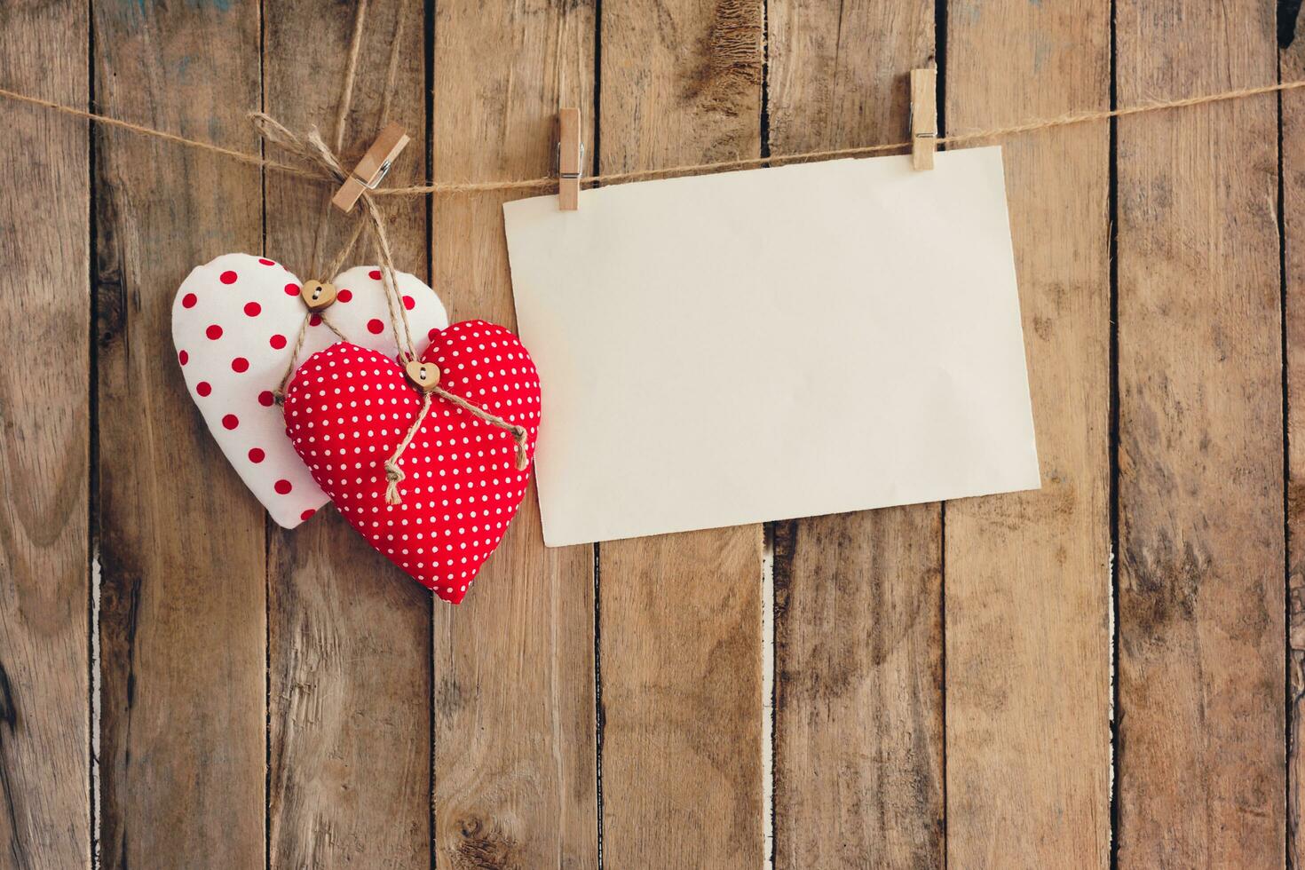 Heart and empty paper hanging on wood background with copy space. photo