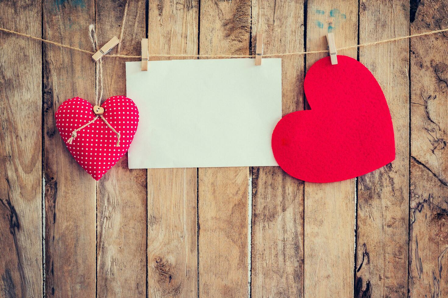 Two heart hanging and paper on clothesline and rope with wooden background photo