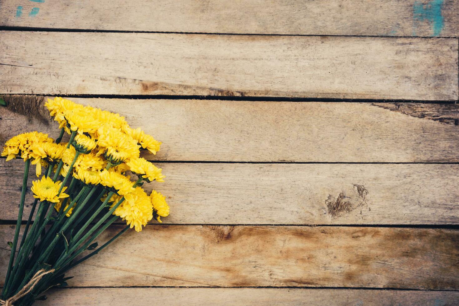 Yellow flowers of bouquet, top view on wooden background texture with copy space photo