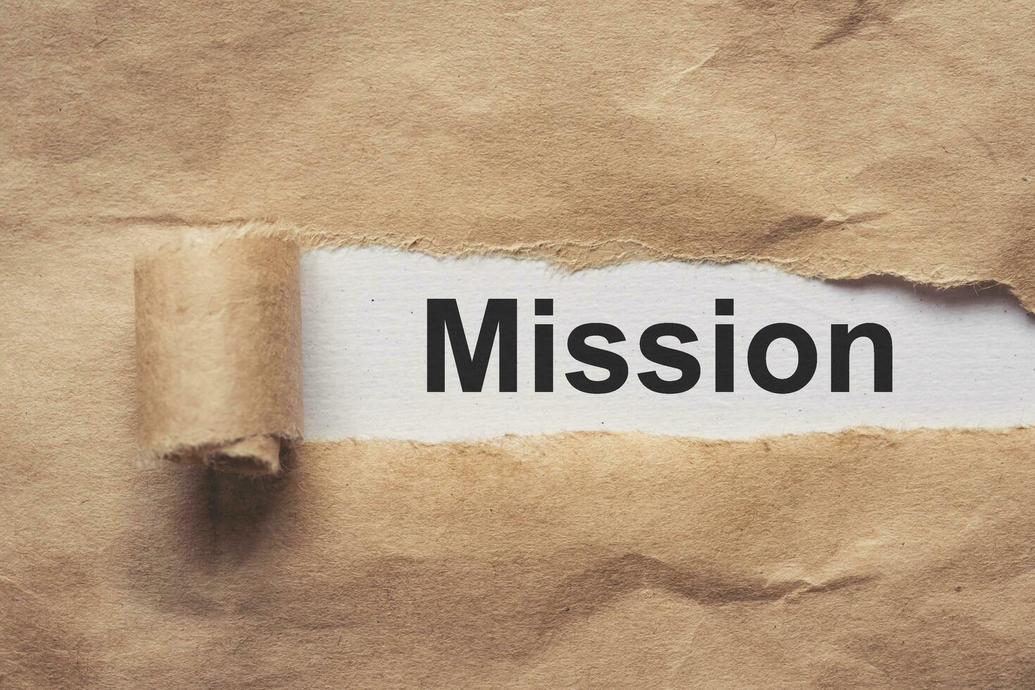 Business and finance. Torn brown paper on a red background, the text - MISSION photo