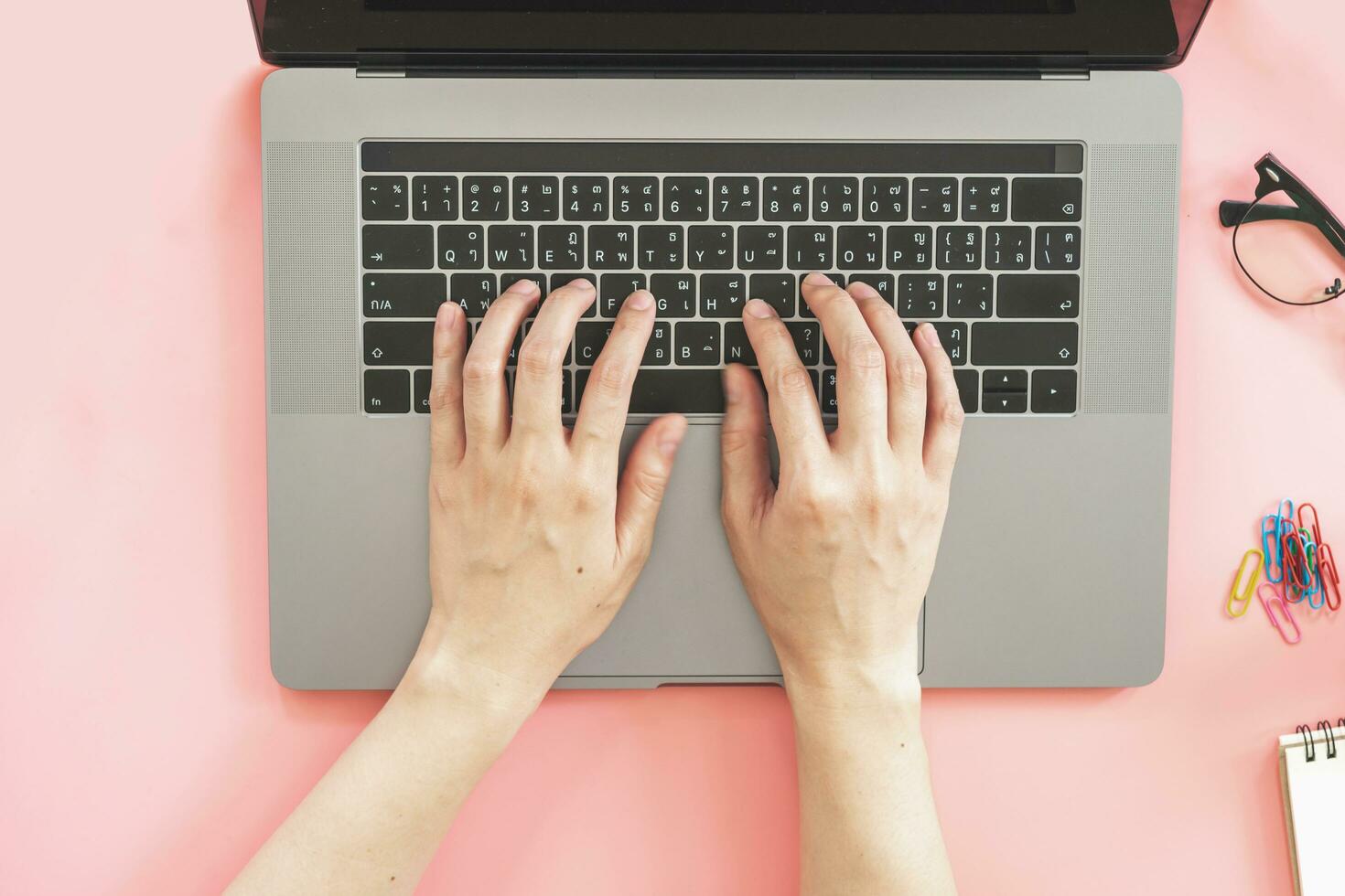 Girl typing on laptop in pink pastel colourful office with accessories photo