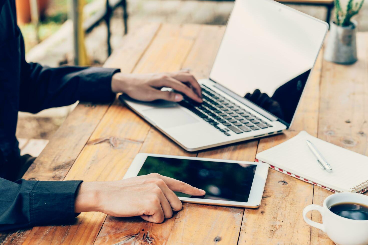 Man using tablet and laptop on table in coffee shop. photo