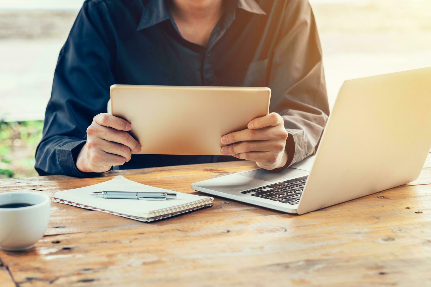 Asia man using tablet and laptop on table in coffee shop with vintage toned filter. photo