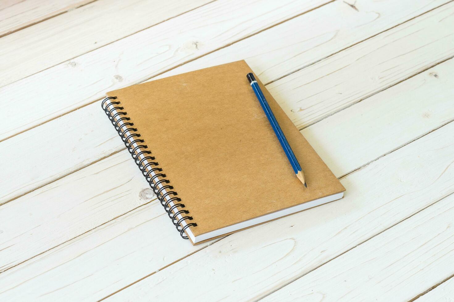 Brown notebook with blank pages and pencil on wood table photo