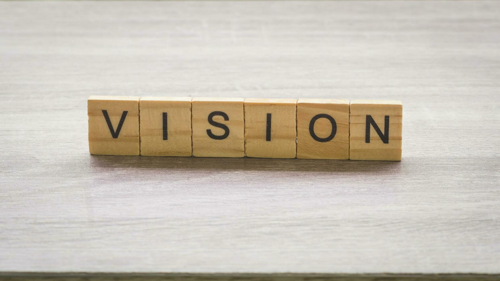 Wooden block with vision massage on wood table background. photo