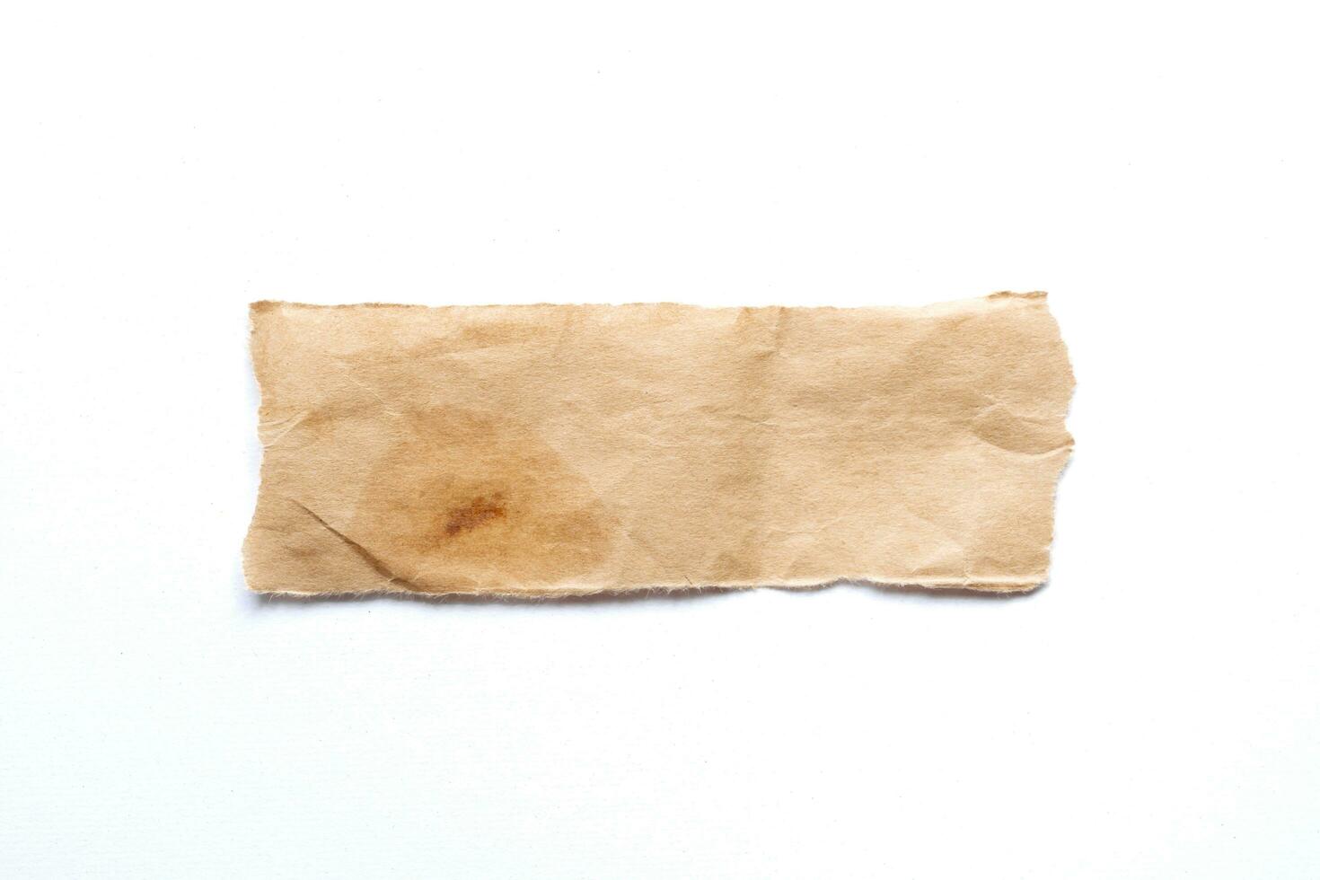 Close up of a ripped piece of brown paper on white background photo