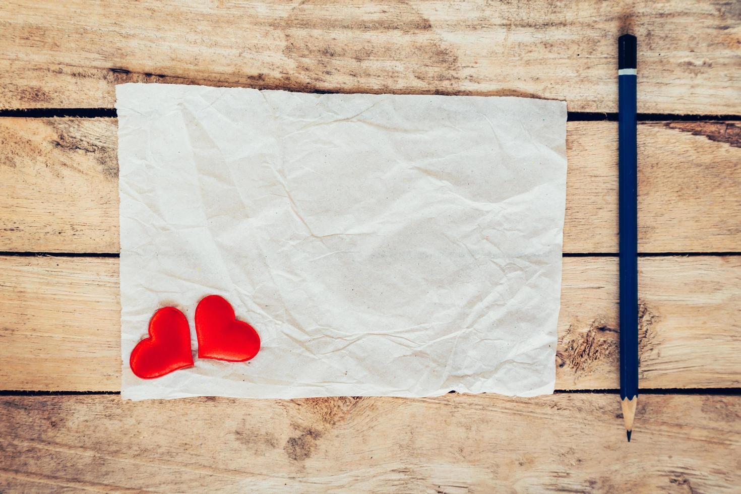 old paper and red heart with pencil on wood background for valentine greeting card. photo