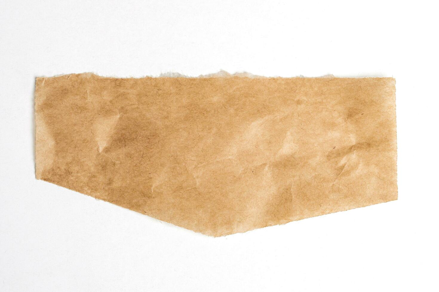 Close up of a ripped piece of brown paper on white background photo